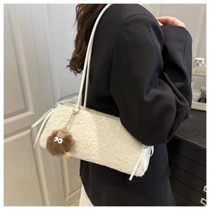Detail of plush off-white lamb wool bag featuring a cute monster doll charm and shoulder strap
