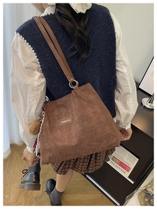 Détail du sac cabas en velours côtelé marron avec lanières en cuir et pompon