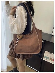 Detailed view of large brown suede tote bag featuring a cute plush bear pendant accessory