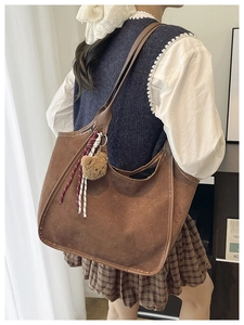 Close-up of brown suede hobo bag with cute plush bear charm and woven rope detail
