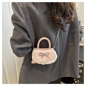 Mini borsa rosa con bordo in pizzo e fiocco argento indossata da una modella