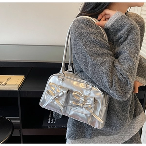Detail of silver metallic shoulder bag with bow pockets worn by a model in urban style