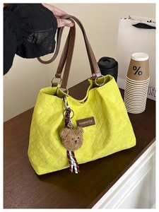 Détail du sac cabas matelassé jaune citron avec anses en cuir marron et pendentif