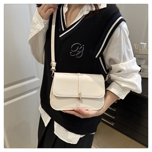 Detail of cream baguette shoulder bag with gold metal buckle and leather strap