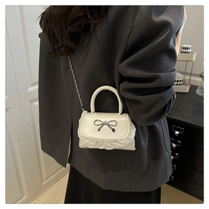 Dettaglio mini borsa bianca in PU con pizzo e fiocco in metallo su blazer