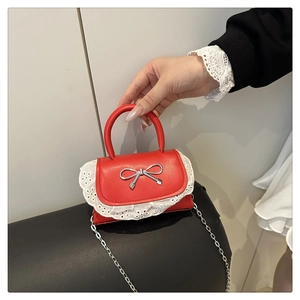 Dettaglio di una borsa rossa piccola con pizzo bianco e decorazione a fiocco