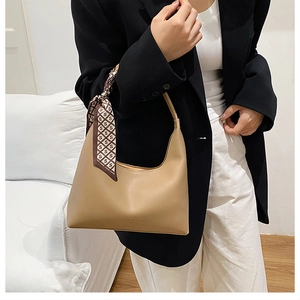Détail du sac sous le bras demi-lune kaki avec un foulard en soie et une texture en cuir