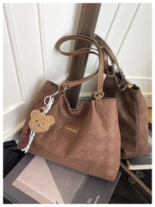 Détail d'un sac cabas marron matelassé avec étiquette en cuir et joli pendentif d'ours peluche