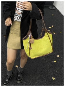 Close-up of yellow canvas tote with brown leather trim and cute bear charm detail