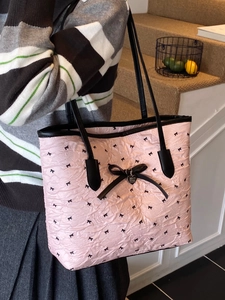 Sac cabas rose à nœuds noirs et pendentif cœur porté à l'épaule par le mannequin