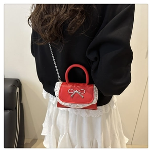 Dettaglio mini borsa rossa con fiocco argento, pizzo bianco e tracolla a catena