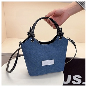 Détail du sac seau en denim bleu avec poignées nouées et œillets métalliques argentés