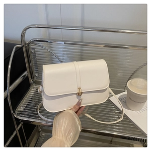 Close-up of cream faux leather baguette bag featuring elegant gold metal lock buckle