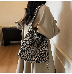 Detailed side view of leopard print canvas tote bag with fashion label and wide strap