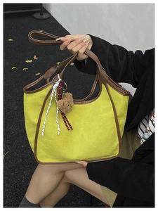 Detail of yellow tote bag with brown faux leather trim and cute plush bear charm
