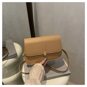 Detail of camel brown baguette bag with golden metal twist lock and smooth leather texture