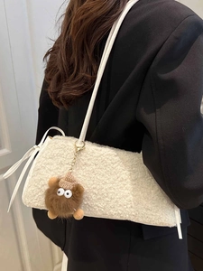 White faux fur hobo bag with a cute brown monster charm and slim leather shoulder strap