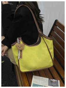 Detail of suede bucket bag in yellow with brown leather trim and cute bear charm