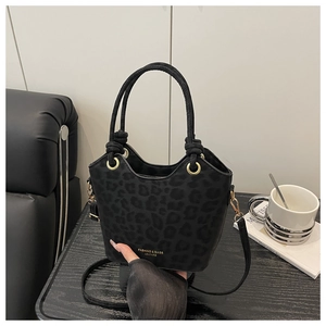 Close-up of black leopard print bucket bag with gold lettering and round handles