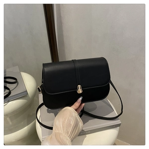 Detailed macro view of black matte leather baguette bag with premium gold metal buckle