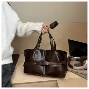 Dettaglio della borsa tote marrone scuro in ecopelle lucida con fibbie argentate