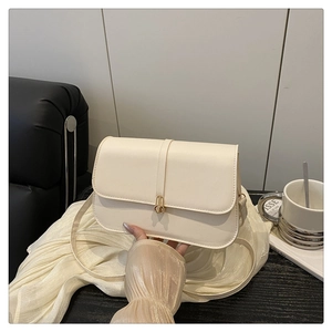 Detail of elegant cream-colored flap bag with golden circular buckle and smooth leather texture