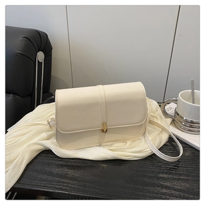Detail of cream-white leather baguette bag with golden clasp and adjustable strap