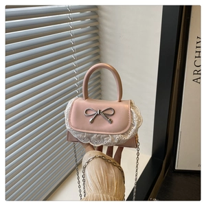Dettaglio mini borsa rosa con pizzo, fiocco metallico e tracolla a catena sottile