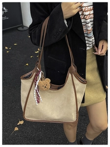 Detail of suede tote bag with brown leather straps and cute plush bear charm accessory