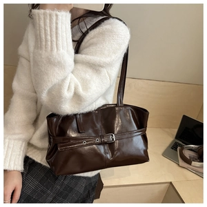 Dettaglio di una borsa tote marrone scuro lucida con fibbia decorativa e interno capiente