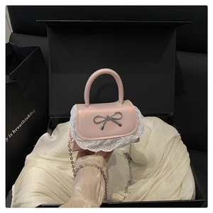 Dettaglio della borsa in pelle rosa con bordo in pizzo bianco e fiocco metallico argento