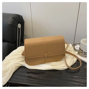 Close-up of camel leather baguette bag with a golden cylindrical twist lock and strap