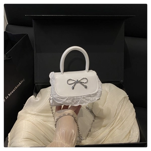 Dettaglio mini borsa bianca con bordi in pizzo e chiusura a fiocco argentata