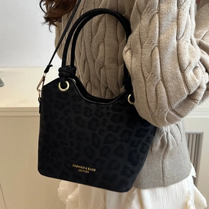 Chic black leopard print bucket bag with gold hardware and woven handles for casual commute