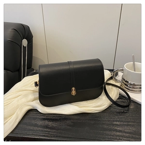 Detailed view of black leather baguette bag with gold metal buckle and smooth saddle shape