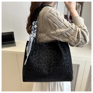 Detail of leopard print tote bag with woven handle and blue silk scarf on model