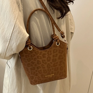 Brown leopard print bucket bag with gold rings shown on a model in a trench coat