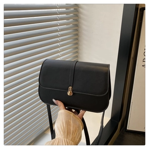 Close-up of black baguette bag with gold metal lock and smooth leather texture