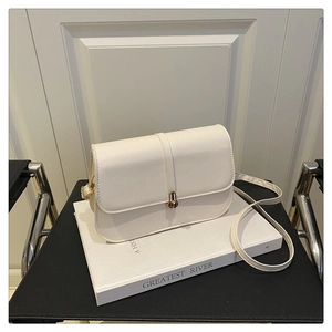 Detail of a creamy white baguette bag featuring a gold twist lock and slim shoulder strap