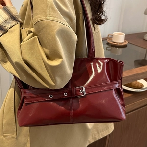 Borsa tote alla moda in pelle verniciata bordeaux abbinata a un trench-coat