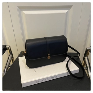 Detail of black leather baguette bag with a stylish gold-toned metallic lock closure