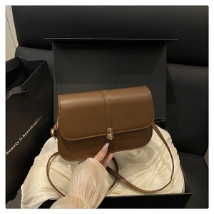 Close-up of retro brown leather baguette bag with gold round buckle in gift box