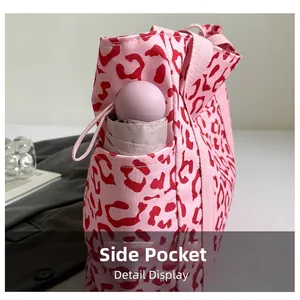 Detail of leopard print tote bag side pocket with a small pink folding umbrella inside