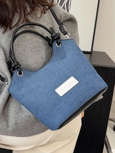 Sac seau minimaliste en denim avec garniture en cuir noir et poignée porté par mannequin