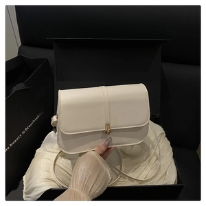 Detail of a creamy white baguette bag with a gold twist lock and elegant gift packaging