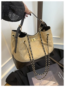 Detail of color-block canvas and black patent leather bucket bag with quilted stitching