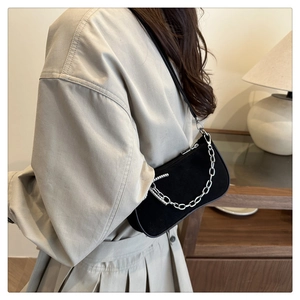 Detail of black suede hobo bag with chunky silver chain strap on a female model