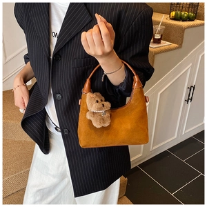 Brown suede hobo bag with teddy bear charm shown on model for realistic size reference