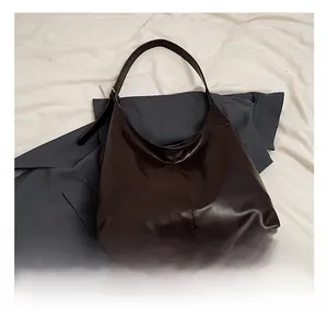 Detailed view of dark brown leather tote bag with vertical stitching and matte finish