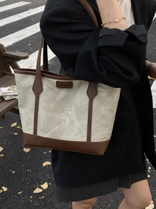 Large canvas and brown leather tote bag for women shown in an urban street style setting